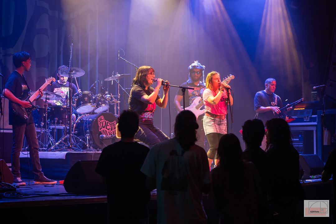 Volle band met twee zangeressen op het podium, gezien over het publiek heen — foto: GEKfoto